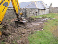 The investigation work begins. The surface is scraped back to reveal the flagstone covers over the water channel